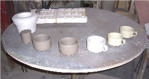 This photo shows the complete process of creating a china product. Watery clay mixture compressed to eliminate water and air; clay placed in mold; leadless glaze applied; 1st firing; and final firing after decals applied.